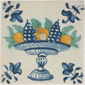 Antique Delft tile with a polychrome fruit bowl containing grapes and pomegranates, 17th century