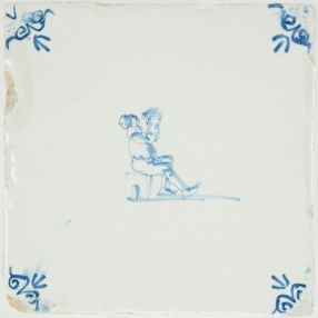Antique Delft blue tile showing a seated man drinking, 17th century