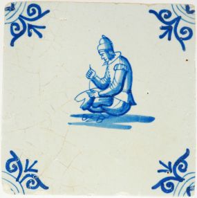 Antique Delft wall tile with a seated tailor at work, 17th century